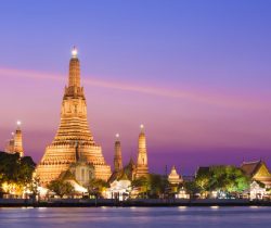 The illuminated temple of Wat Arun on the Chao Phraya river at sunset in Bangkok, Thailand