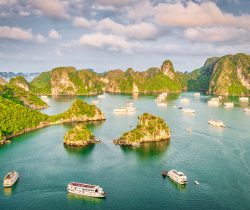 Scenic view from above over Halong Bay with cruising Tourboats and Tourist Passenger Ships in warm late afternoon light. Halong Bay is popular for the fantastic limestone karsts and isles. Halong Bay, Quang Ninh Province, Northern Vietnam, Vietnam, Southeast Asia